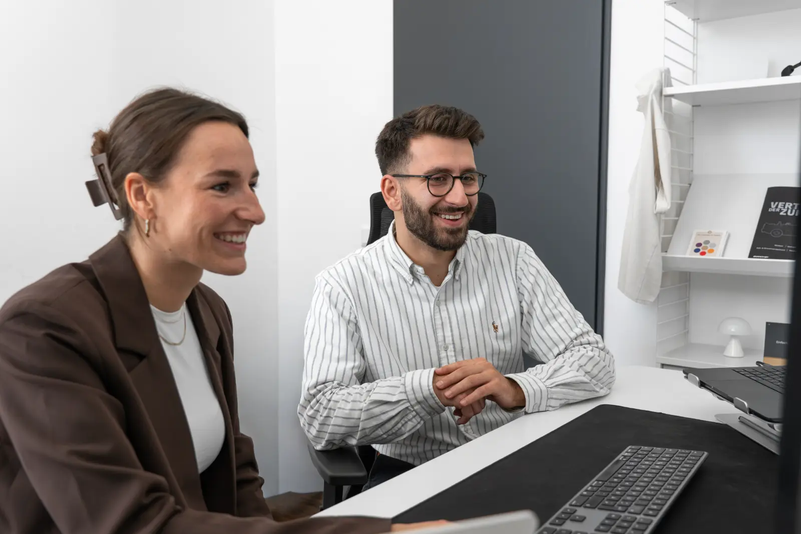 Zwei Kollegen lachen gemeinsam am Monitor