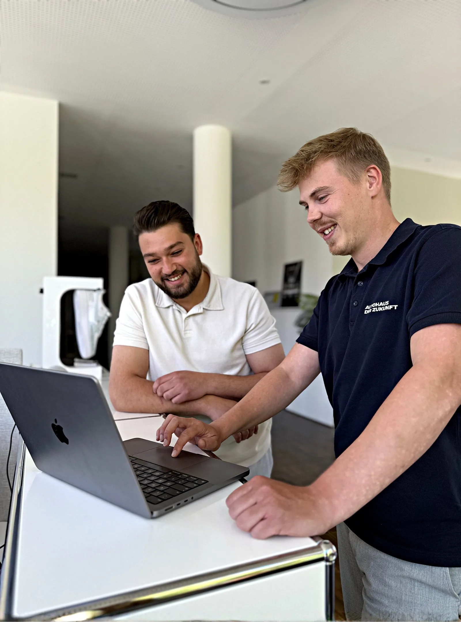 Zwei Kollegen lachen gemeinsam am Laptop